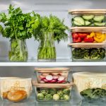 Ripiano del frigorifero ordinato con contenitori di vetro e erbe aromatiche