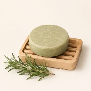 Shampoo solido verde su un piattino di legno con rametto di rosmarino
